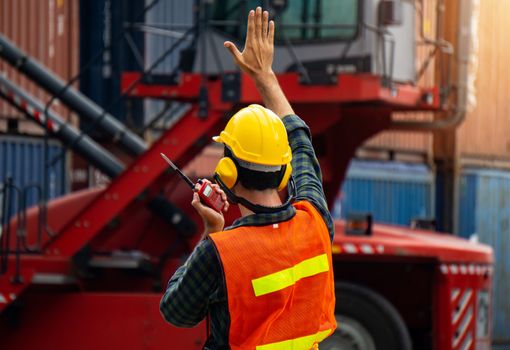 industrial worker is controlling container loading by walkie talkie in import-export business.