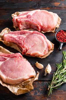 Organic Porco Iberico French Racks set over old rustic dark wood table with herbs and ingrefients top view vertical close up.