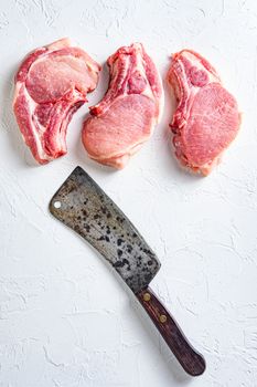 Organic bio Raw pork chops set for grilling, baking or frying, Fith butcher cleaver ower textured white background. Vertical concept