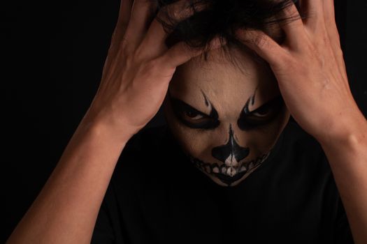 Southeast asian man with skull face makeup on black background, portrait photography
