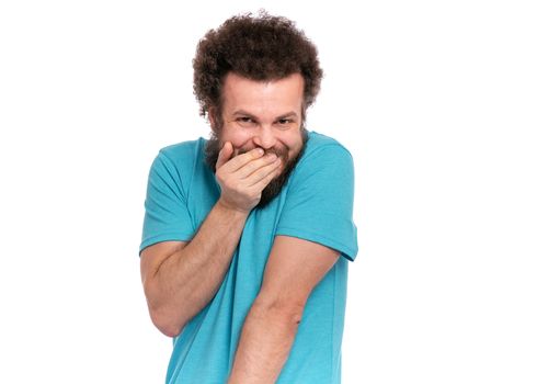 Crazy bearded modest and embarrassed Man with funny Curly Hair, isolated on white background. He is Shy, covering his mouth with hand and looking in camera. Emotions and signs concept.