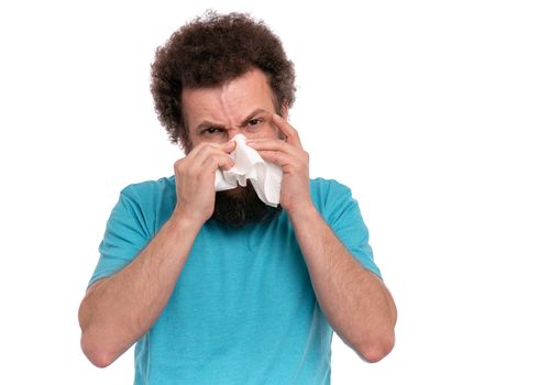 Crazy bearded Man with funny Curly Hair has a runny nose, isolated on white background. Sick guy with paper napkin blowing nose. People, healthcare, cold or Allergy concept.