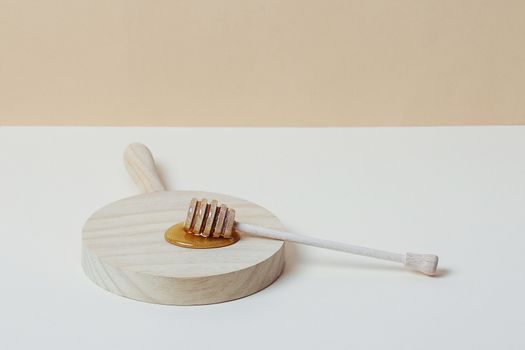 Honey dipper on a wooden tray. Copy space.