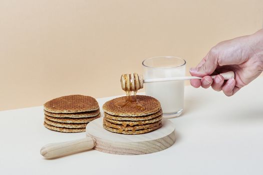 Female hand pouring honey over a pile of waffles. Copy space.