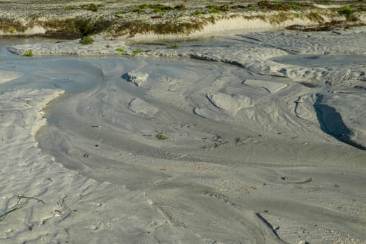 Sandy beach in Wells next the Sea. The tide has just gone out and the beach is muddy with sea water.