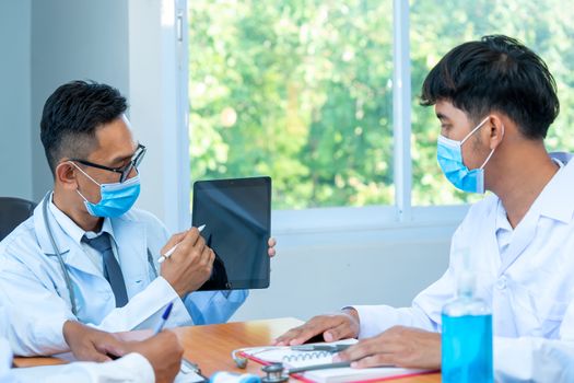 Group of doctor wearing protective surgical mask and discussing work together at the table during meeting at hospital,Epidemic virus outbreak concept.