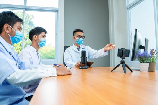 Group of doctor wearing protective surgical mask discuss work together and looking at online presentation on computer at hospital.