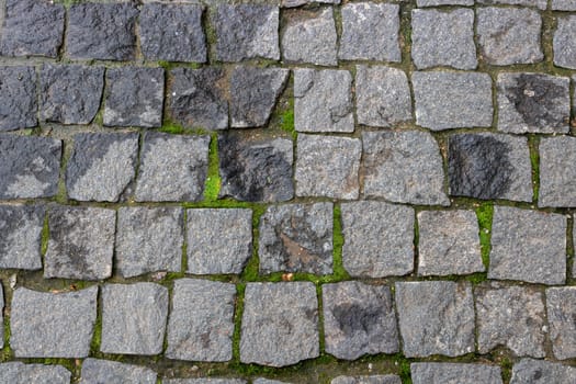 Granite paving stone background of the sidewalk. Abstract background of an old cobblestone street close-up.