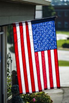 Vertical shot of an American Flag hanging vertically in front of a business.