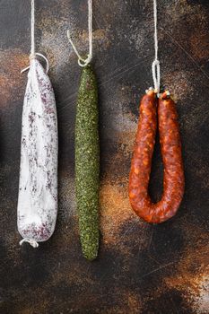 Dry cured chorizo and fuet salami sausages hanging on dark background.