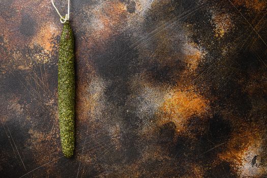 Spanish dry salami fuet in herbs on old metall background with space for text.