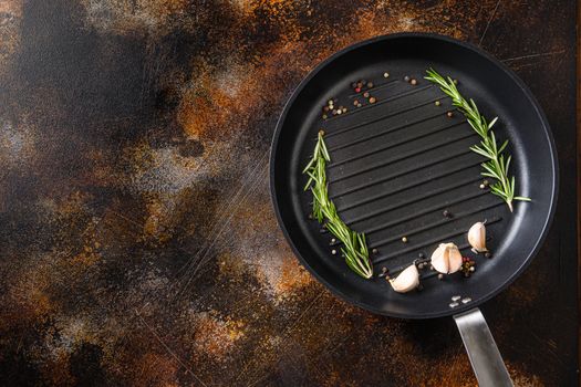 grill pan or skillet on rustic metall surface with herbs for cooking top view concept for text or objects.