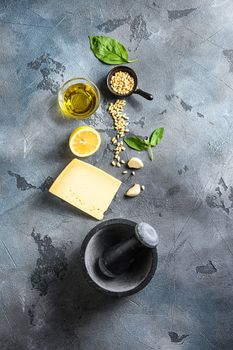 italian ingredients for pesto genovese sauce background, healthy food Basil, olive oil, parmesan, garlic, pine nuts. concept on a vintage stone grey background from above with copy space.