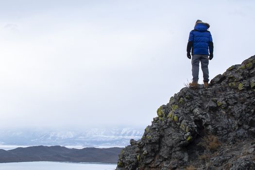 Happy man standing on cliff, man looking at landscape view