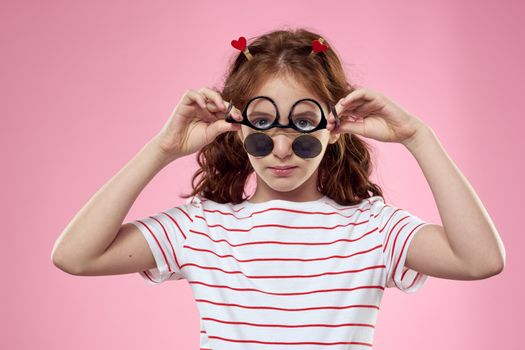 Cheerful girl with pigtails sunglasses striped t-shirt lifestyle pink background. High quality photo