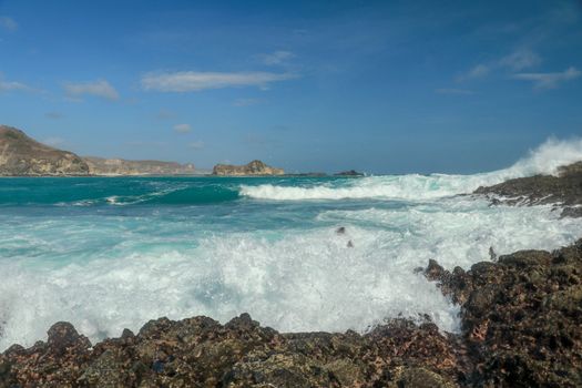 Waves splashing on a headland around Tanjung Aan beach. Dangerous phenomenon on a heavenly beach. Water is bubbled from the strength of the crushing waves. Beauty of the nature.