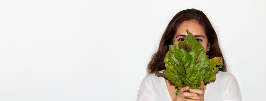 Real young man with a bunch of radishes covering his face. Isolated on a white background. Copy space