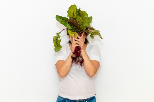 Real young man with a bunch of radishes covering his face. Isolated on a white background. Copy space