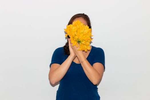 Real young man with a bunch of pumpkin flower covering his face. Isolated on a white background. Copy space