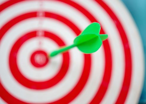 Green arrow strikes center of goal on blurred background - Successful business goal idea.