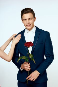 A man in a suit with a rose in his hands a gift date light background. High quality photo