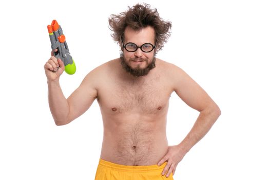 Crazy bearded Man with funny Haircut in eye Glasses, ready for fun at sunny beach. Happy and silly tourist, isolated on white background. Cheerful naked man holding Water Gun.