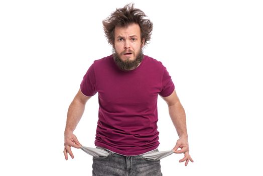 Crazy bearded Man with funny Haircut showing his empty pockets, turning his pockets inside out. Portrait of sad Guy, isolated on white background. Unhappy face expression. Money concept.