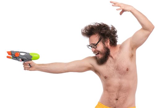 Crazy bearded Man with funny Haircut in eye Glasses, ready for fun at sunny beach. Happy and silly tourist, isolated on white background. Cheerful naked man holding Water Gun.