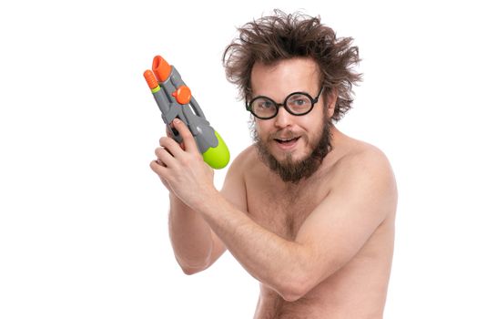 Crazy bearded Man with funny Haircut in eye Glasses, ready for fun at sunny beach. Happy and silly tourist, isolated on white background. Cheerful naked man holding Water Gun.
