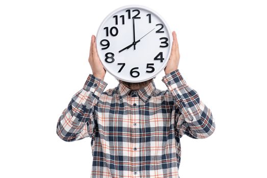 Portrait of Bearded Man in plaid shirt is holding big Clock in front of Head, isolated on white background. Time concept.