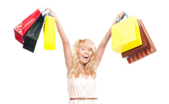 Beautiful and happy young woman standing isolated on white background with shopping bags in her hands over her head. Looking into the camera and laughing.