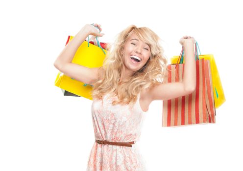 Beautiful and happy young woman standing isolated on white background with shopping bags in her hands. Looking into the camera and laughing.