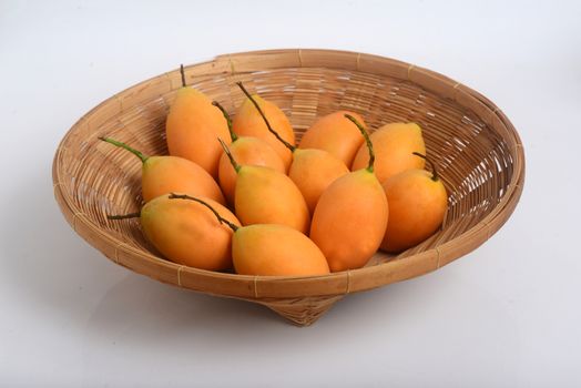 Sweet Marian plum or Plango  in a wicker basket. Yellow-orange color tropical fruits. Thai fruits