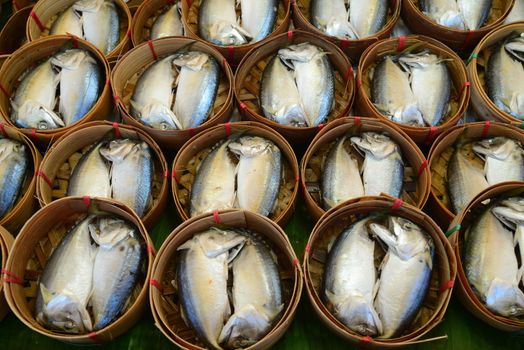 Steamed fish in the bamboo basket on banana leaf in local market samut sakhon of Thailand