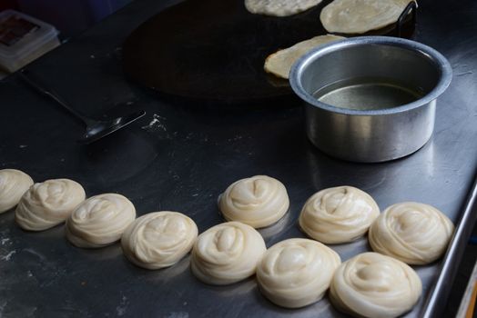 Soft focus of Roti Making with oil, white raw Roti thresh flour by maker
