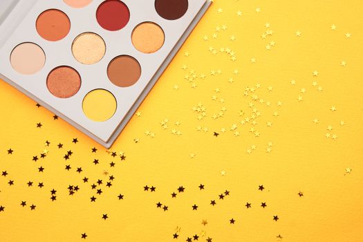 eyeshadow on a yellow background and glitter decorations. High quality photo