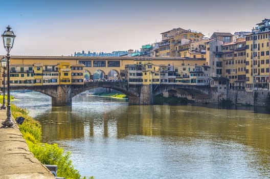 bank of  arno  river crossed by ponte vecchio in hours near the sunset