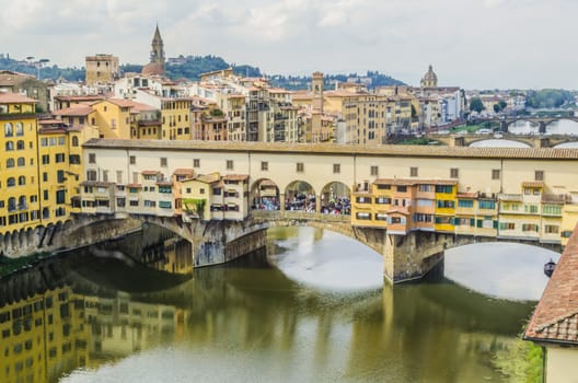 view of the bridge vecchio of florence and successive bridges crossing the river arno and other constructions of the city of the background the mountains of tuscany