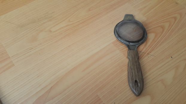 Close up view of chinois with metal gaze place on a wooden floor. This chinois is use for tea infusion in traditional tea services.