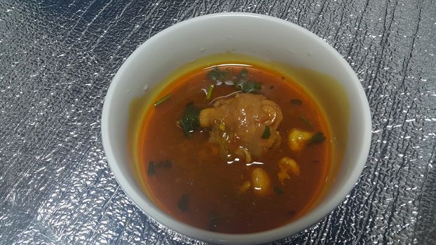 Top view of siri paaye or paya dish garnished with diced ginger, long coriander leaves and fresh sliced lemon. This dish is popular in Pakistan and Bangladesh