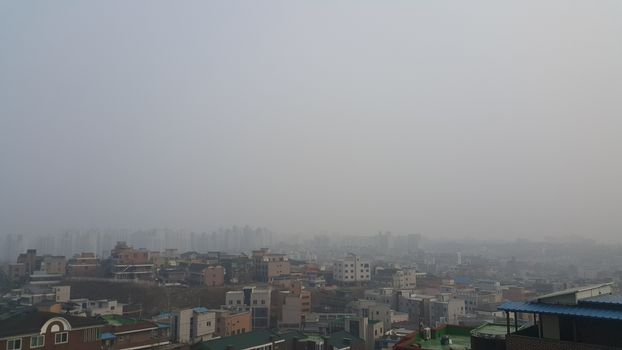 Cityscape aerial view of developed country with  dusty, smogy or amoky background in the sky and skyscraper buildings.