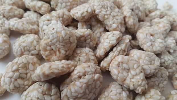 Closeup view of home made Asian sweet food called rewri or rewdi oe sesame seed sweet mad with jaggey and served in a white plate. 