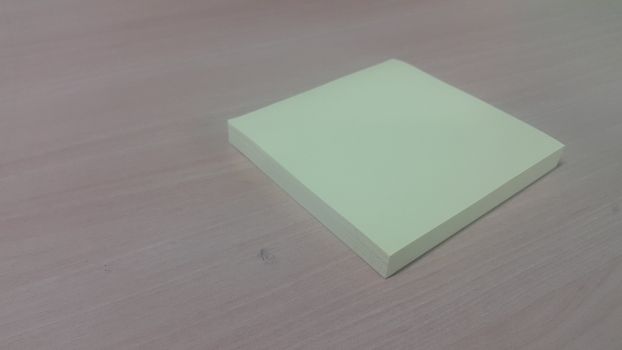 Close-up, selective focus: Yellow sticky note paper placed on a wooden table with copy space for text