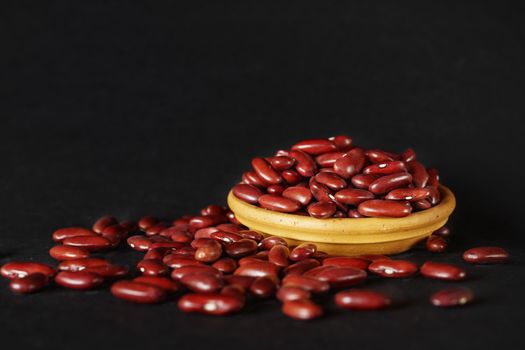 Common red beans -kidney bean - on black background , part of the beans are in a bowl