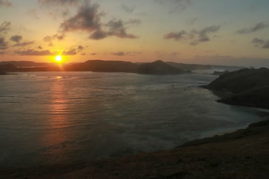 Sunrise view from rock at Tanjung Aan. Rising sun over Tanjung Aan Bay, Lombok, Indonesia. Reflection of the sun's rays on the sea surface. Sunset.