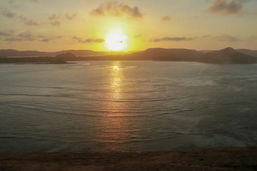 Sunrise view from rock at Tanjung Aan. Rising sun over Tanjung Aan Bay, Lombok, Indonesia. Reflection of the sun's rays on the sea surface. Sunset.