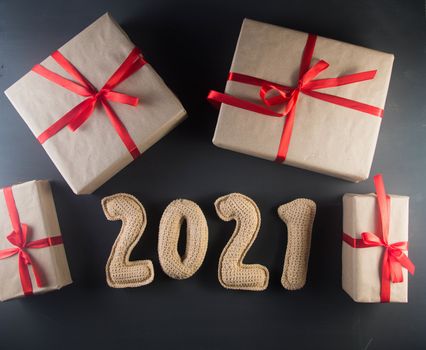 Christmas background with chroched 2021 number and craft paper gift boxes with red ribbons