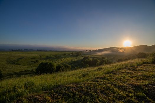 summer sunrise with distand fog in the middle of nowhere.