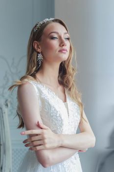 Close-up portrait of a bride in a white wedding dress looks attentively aside.