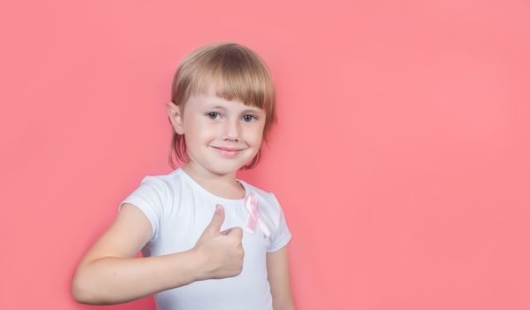 .Little girl showing thumb up wearing white t-shirt and pink breast cancer awareness ribbon